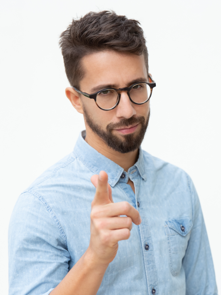 Homem de barba e óculos com um leve sorrizo apontando o dedo indicador